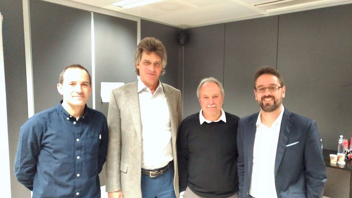 Four men pose together in a meeting room