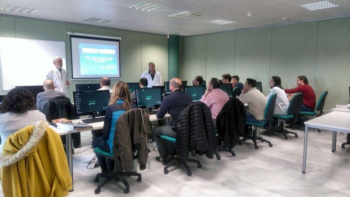 Two teachers in white coats introduce the course to about twenty students sitting at their computers