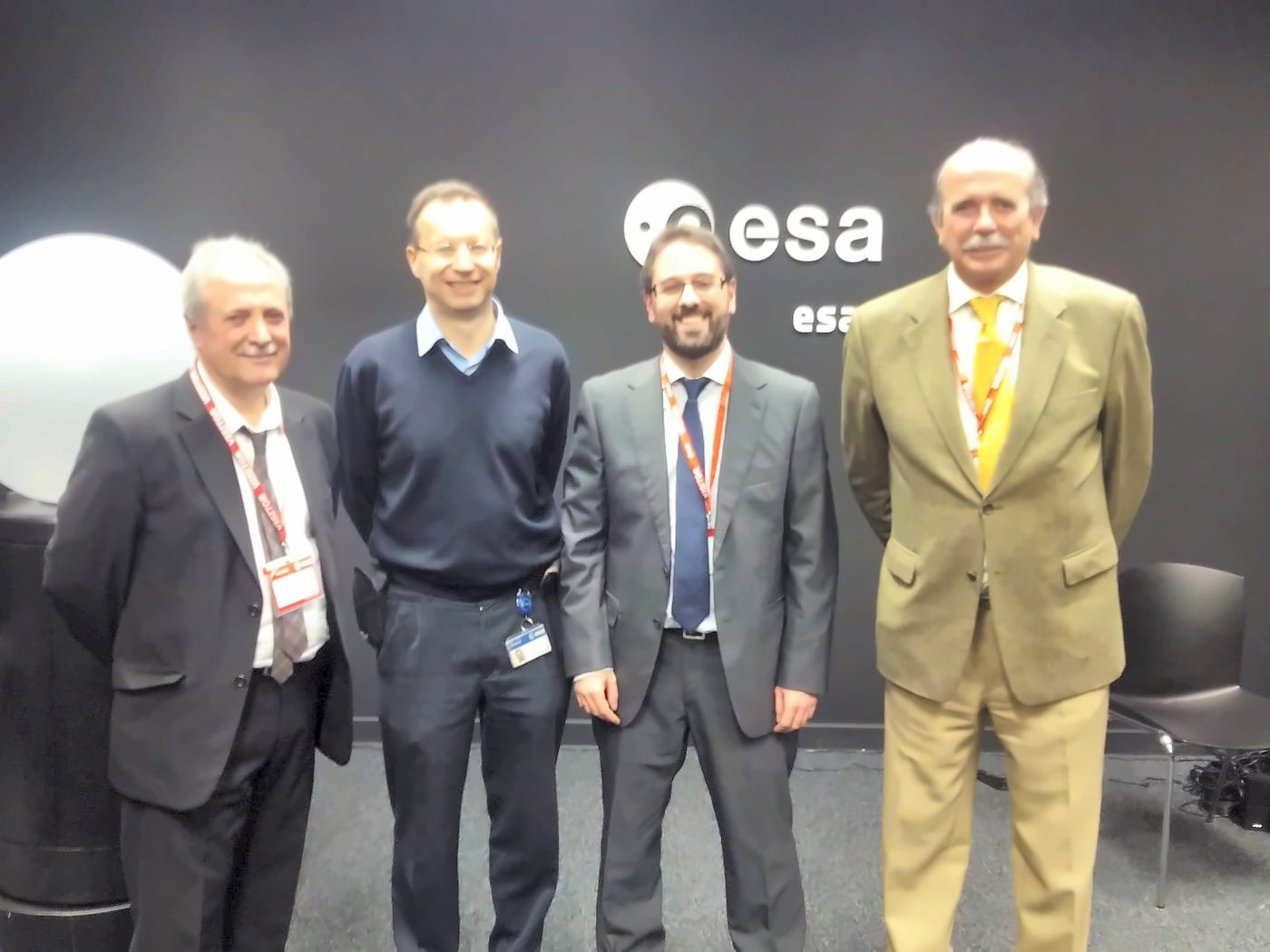 Four men pose in front of the ESA and ESAC logo