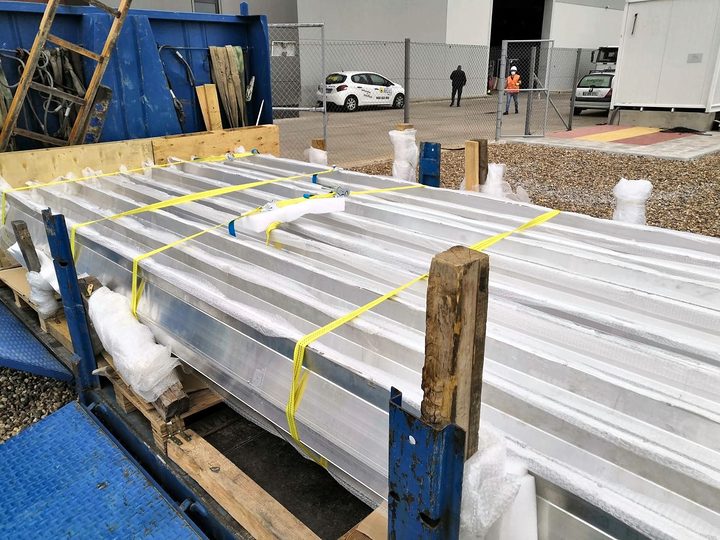 Long rows of mirrors wrapped in film and strapped onto pallets, outdoors