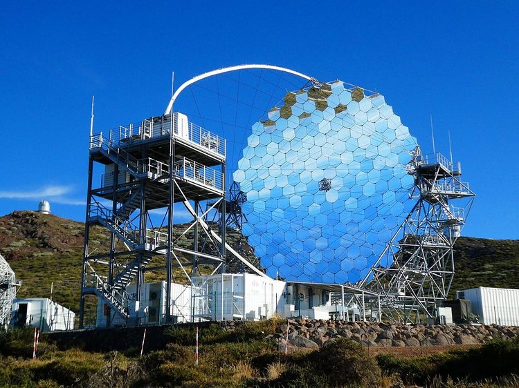 Large telescope with a mirror made of hexagonal segments, its steel structure and the arch that holds the camera, under a blue sky