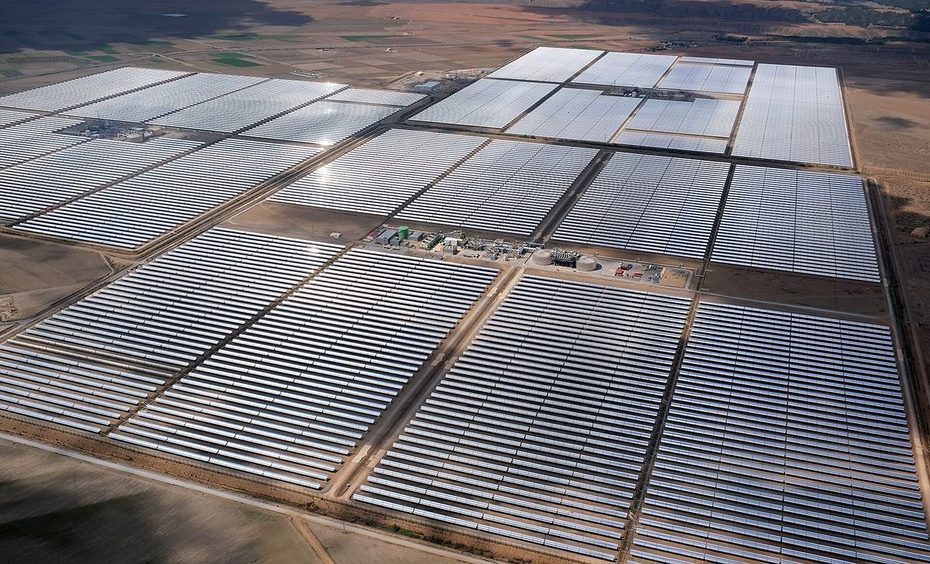 Aerial view of long parallel rows of parabolic trough collectors on a plain