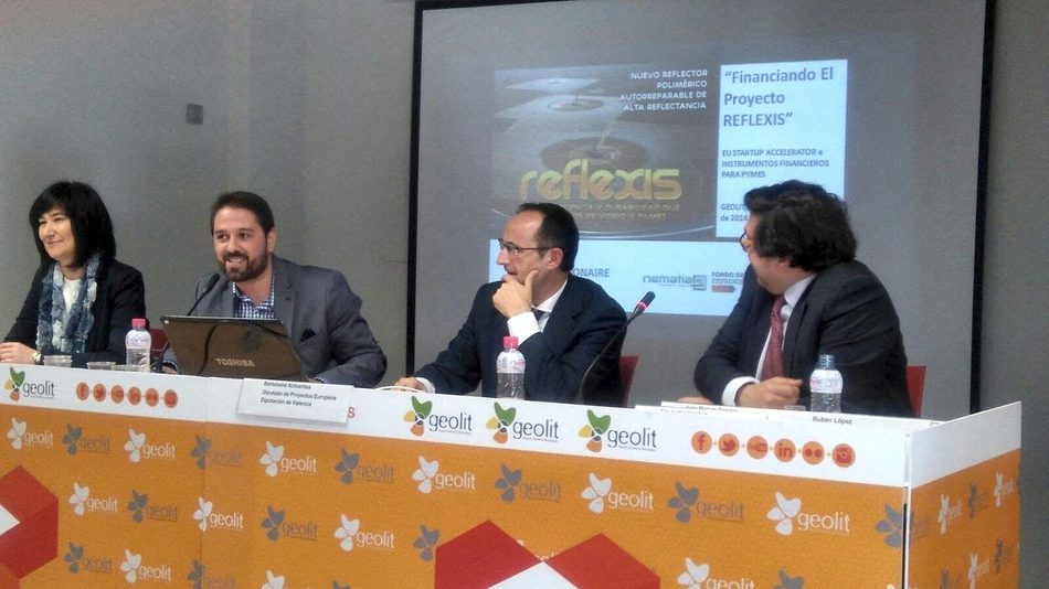 Four speakers at a table, with the presentation “Financing the REFLEXIS project” projected behind them