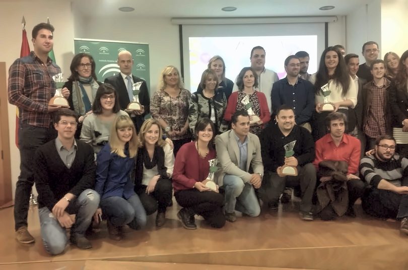 About thirty award winners pose with their trophies in front of a Junta de Andalucía banner