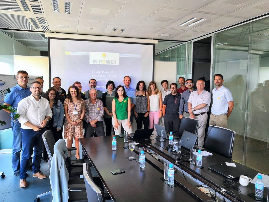 The consortium poses in a meeting room in front of a screen with the IN-POWER logo