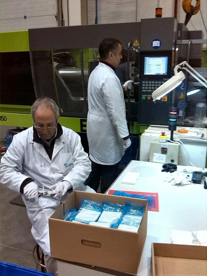 Juan Manuel Donaire, in a white coat, prepares freshly moulded samples next to an injection moulding machine