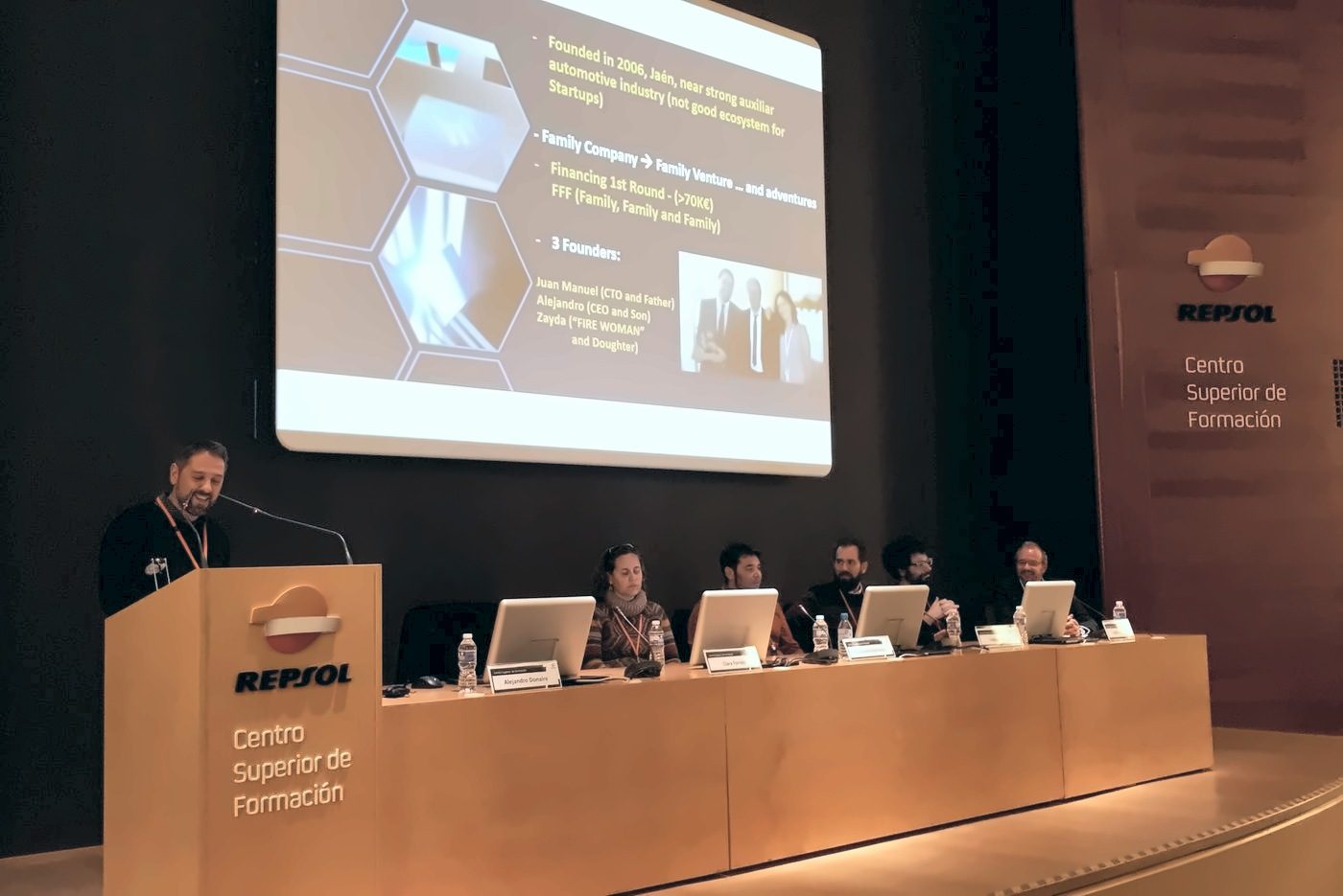 Alejandro Donaire speaks from the Repsol lectern before a panel of speakers, with his presentation projected on the screen