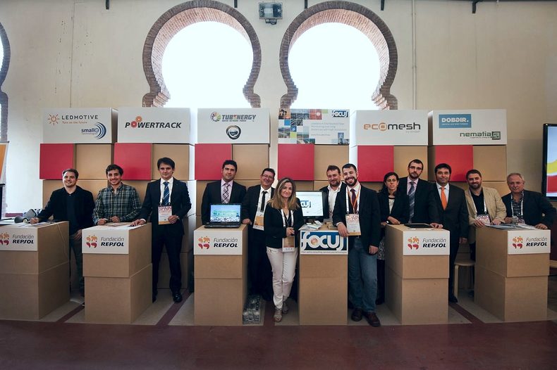 The Entrepreneurs Fund project teams pose in front of their stands in an arcaded venue