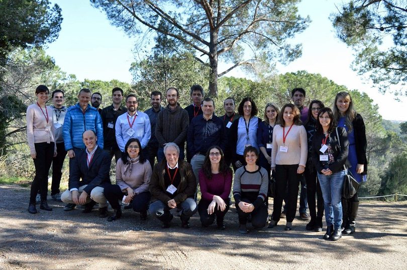 The consortium poses outdoors among pine trees