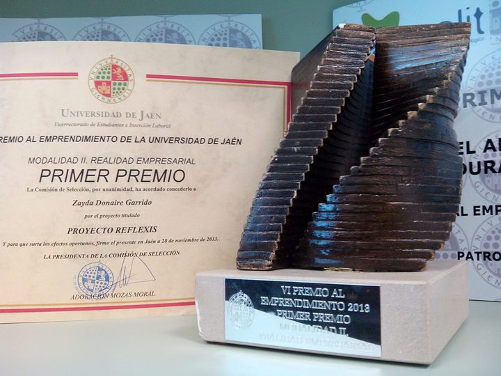 Diploma of the University of Jaén first prize for the REFLEXIS project, next to a wooden trophy