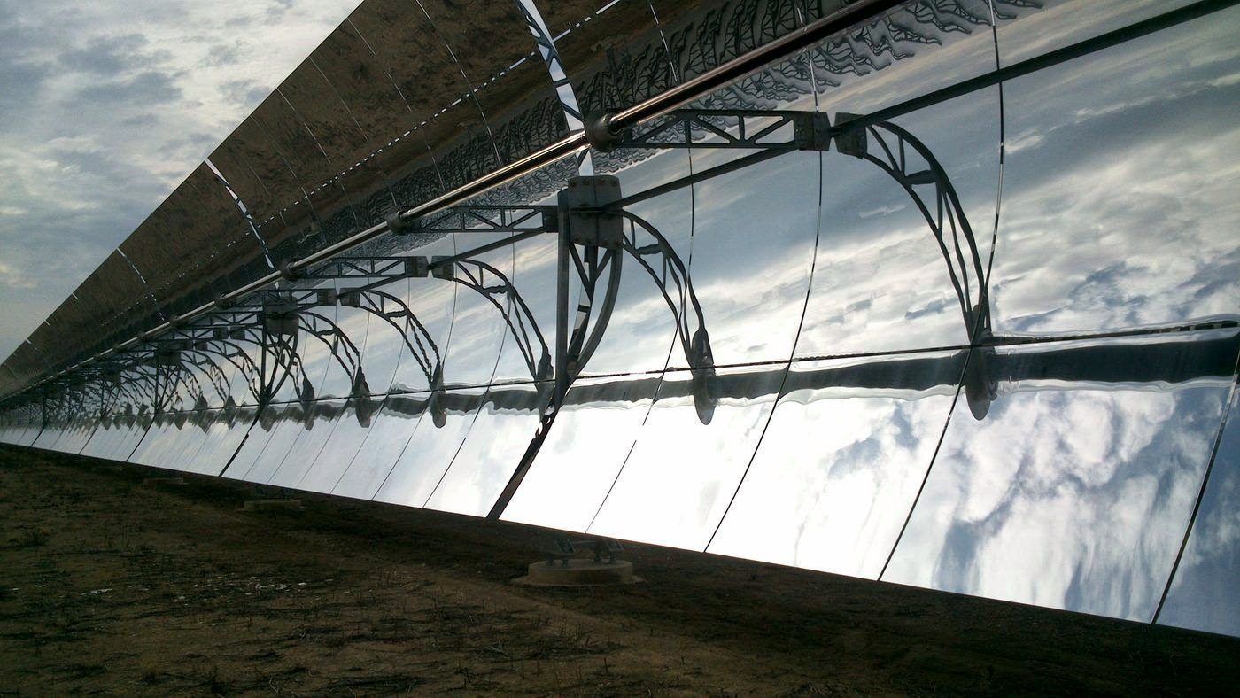 Row of parabolic trough collectors seen close up under a cloudy sky