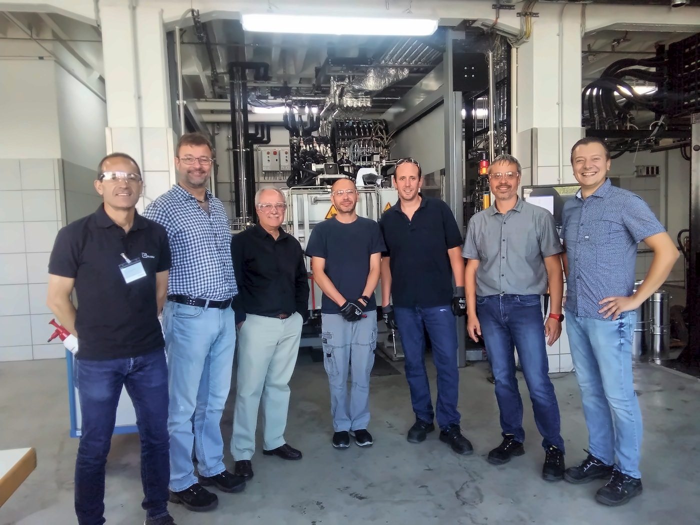 Seven men pose in an industrial building